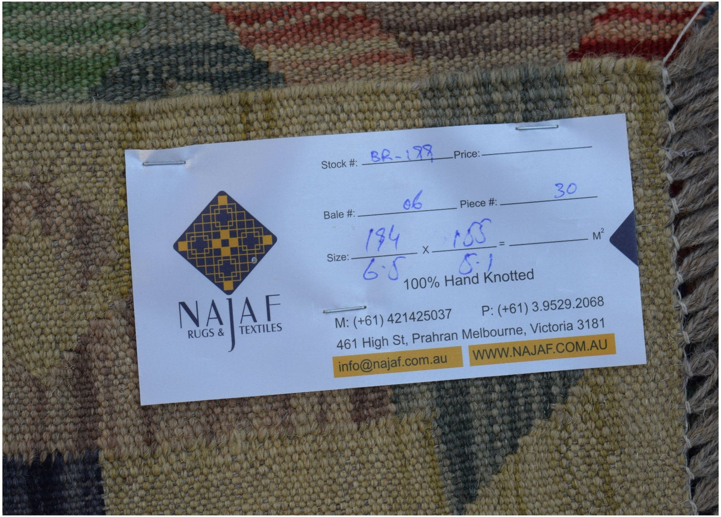 A close-up view of the back of an Afghan Maimana Kilim rug with a product information tag attached.