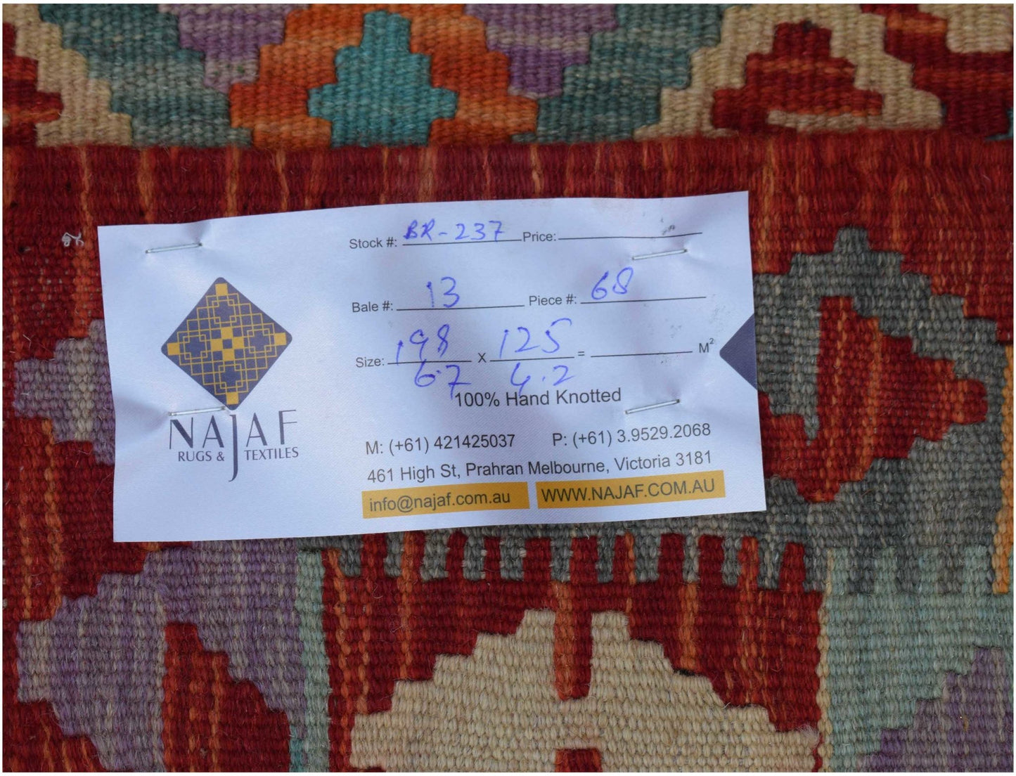 A handwoven Afghan Maimana kilim featuring a geometric pattern in rich red, blue, and purple tones.