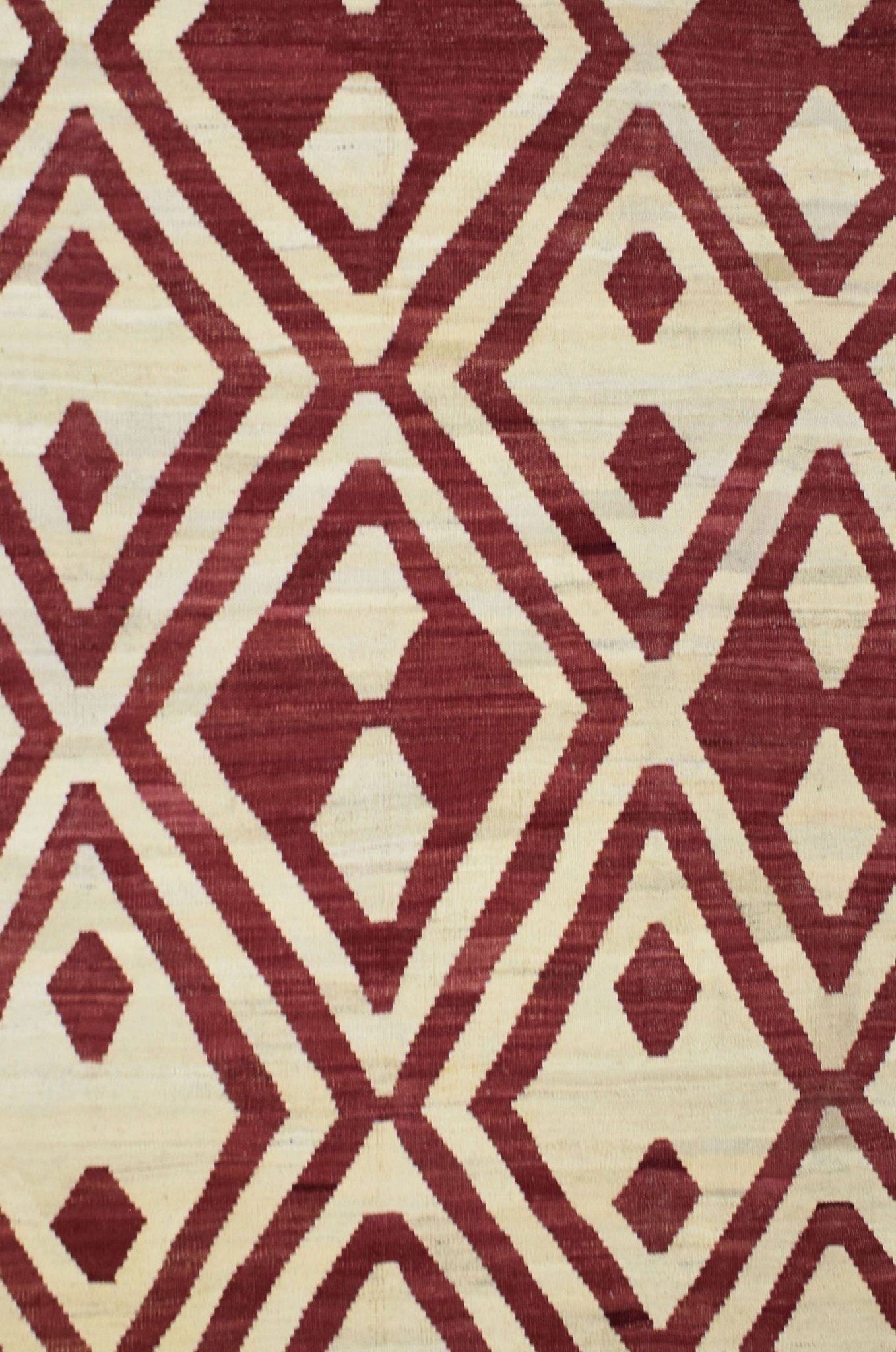 Handmade Afghan Maimana kilim rug featuring a geometric diamond pattern in red and cream wool.