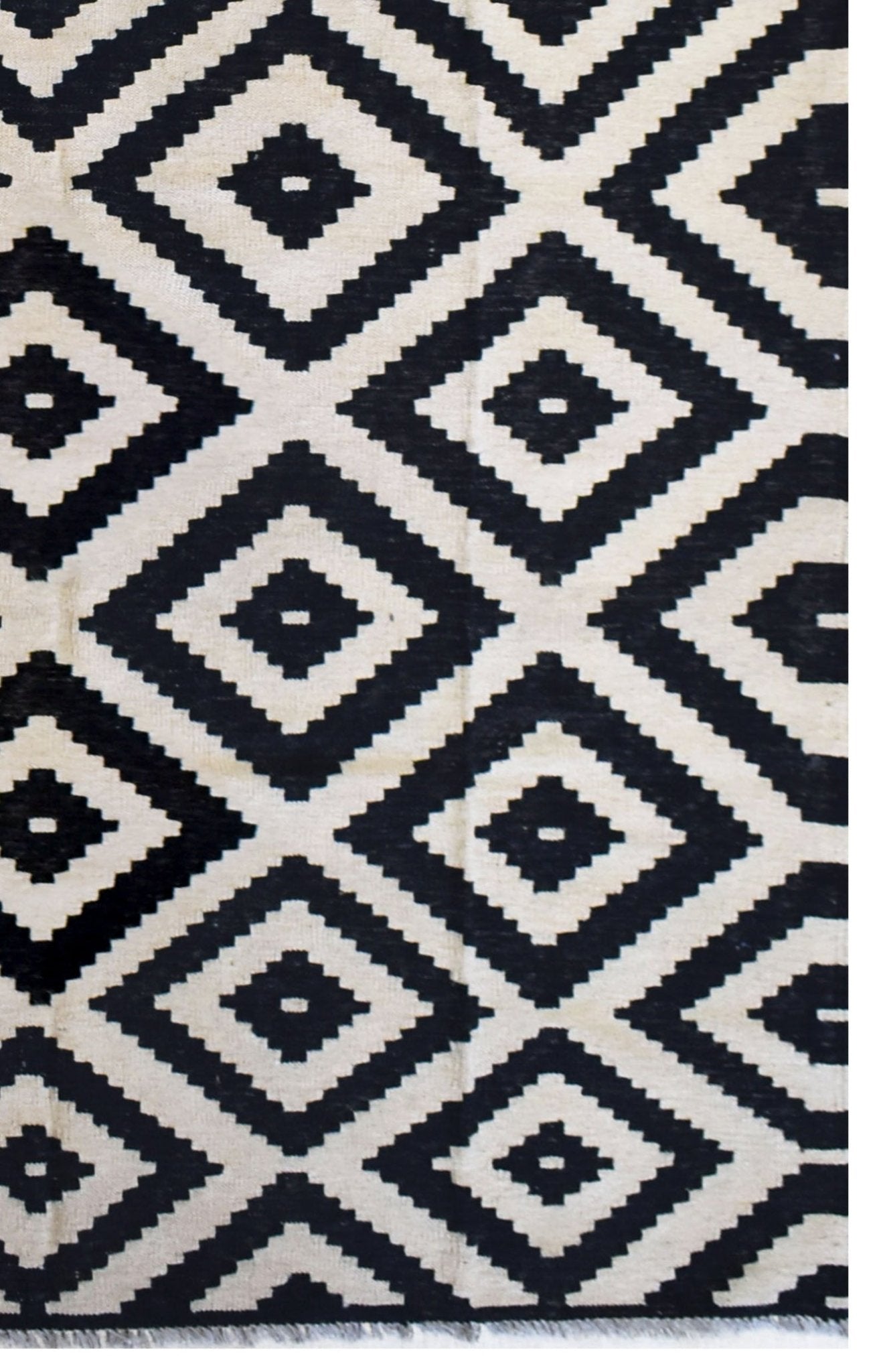 A handmade Afghan Maimana kilim rug featuring a repeating black and cream geometric diamond pattern.