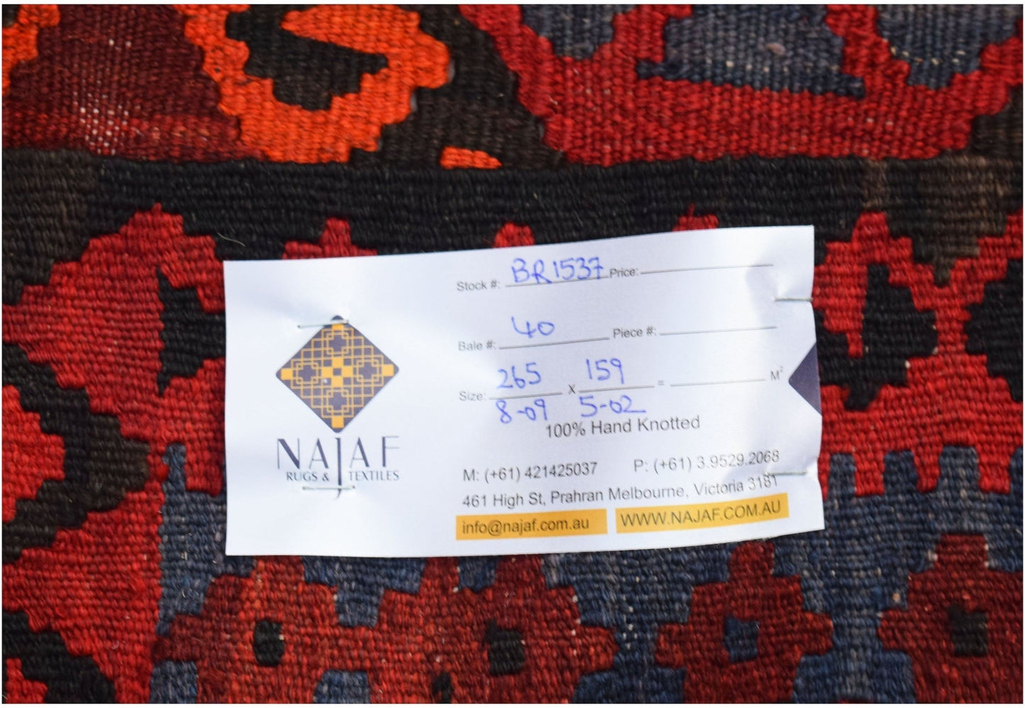 A handwoven Afghan Maimana kilim featuring a geometric pattern in shades of red and dark blue.