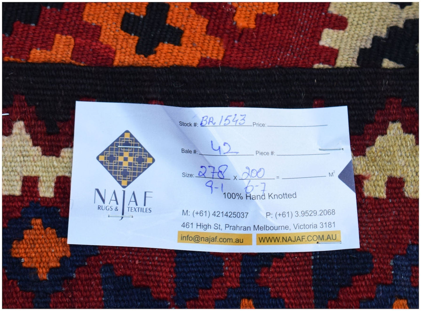 A handmade Afghan Maimana Kilim rug featuring a geometric pattern in red, orange, and dark blue.