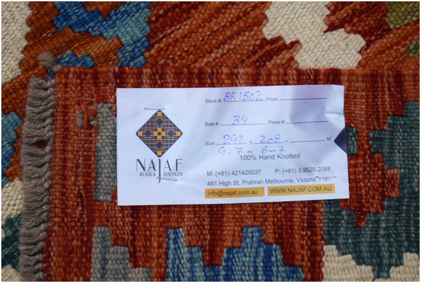 A handwoven Afghan Maimana Kilim rug featuring a geometric pattern in orange, blue, and cream.