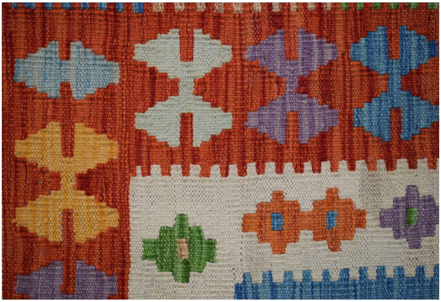Handwoven Afghan Maimana kilim featuring a vibrant geometric pattern on a textured wool surface.