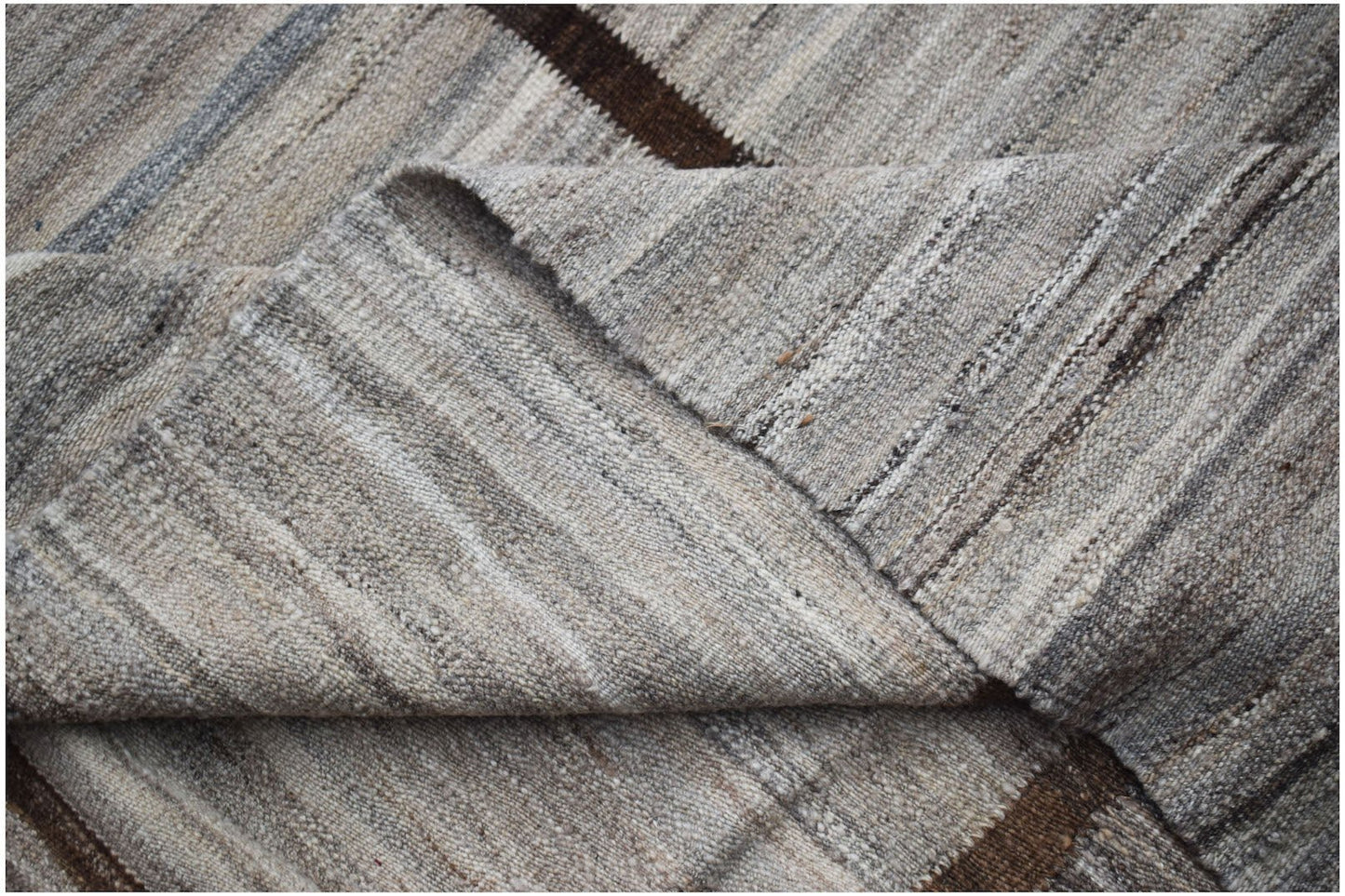 A handwoven Afghan Maimana kilim featuring a flatweave texture and neutral striped pattern.
