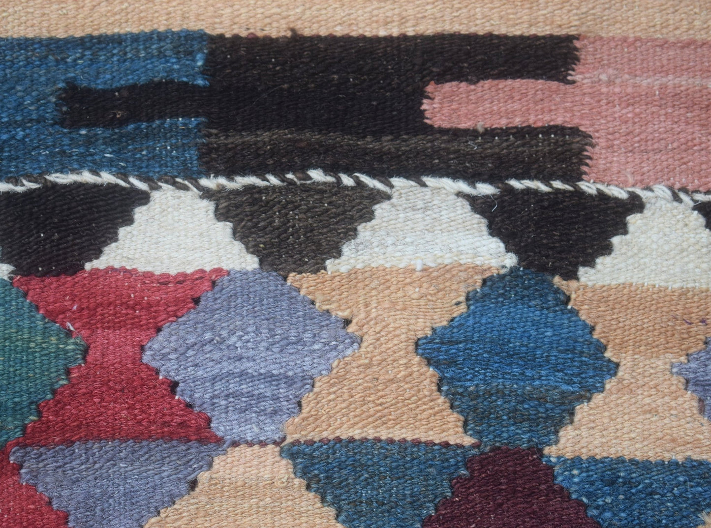 A close-up of a handmade Afghan Maimana kilim runner featuring a geometric pattern in wool.