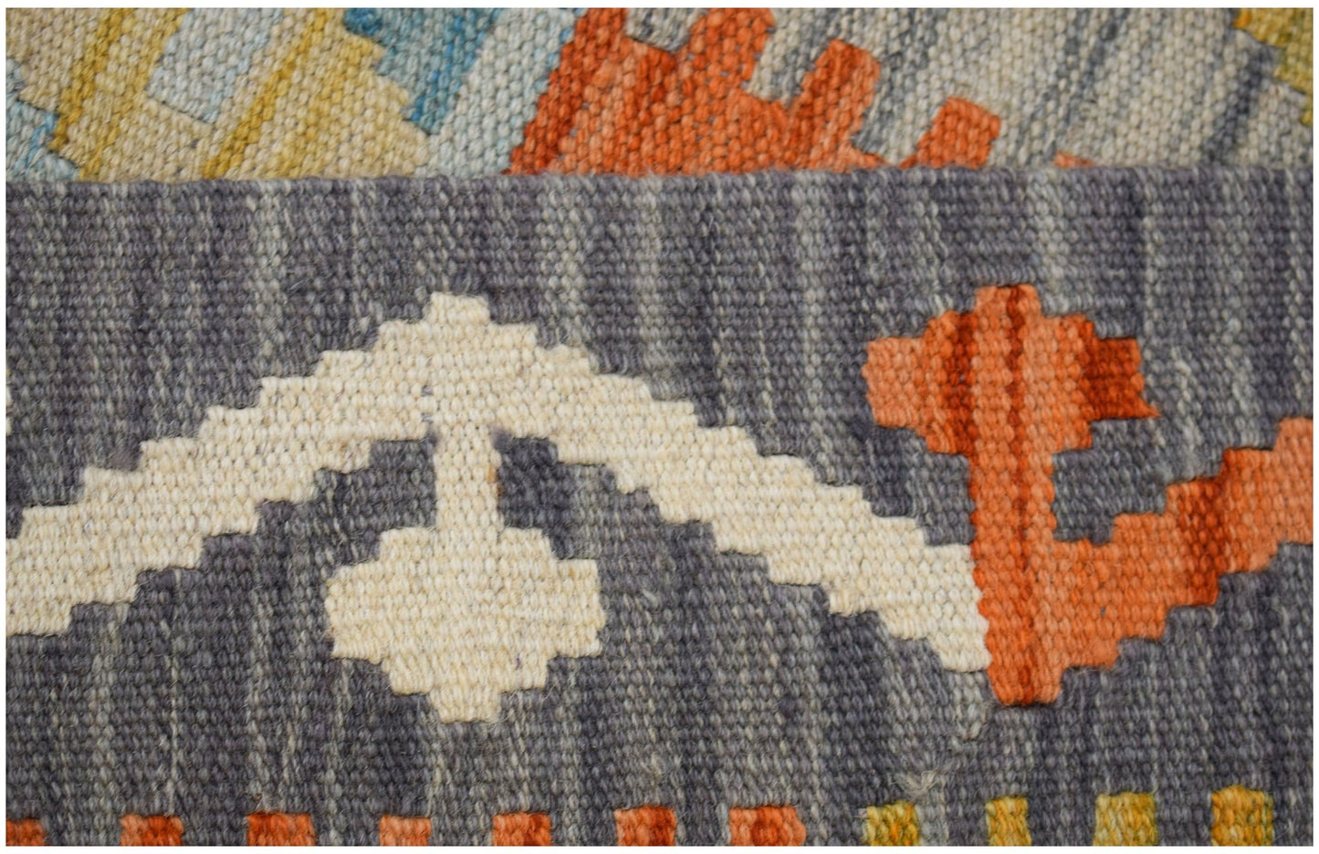 A close-up of a handwoven Afghan Maimana kilim runner featuring geometric patterns in wool.