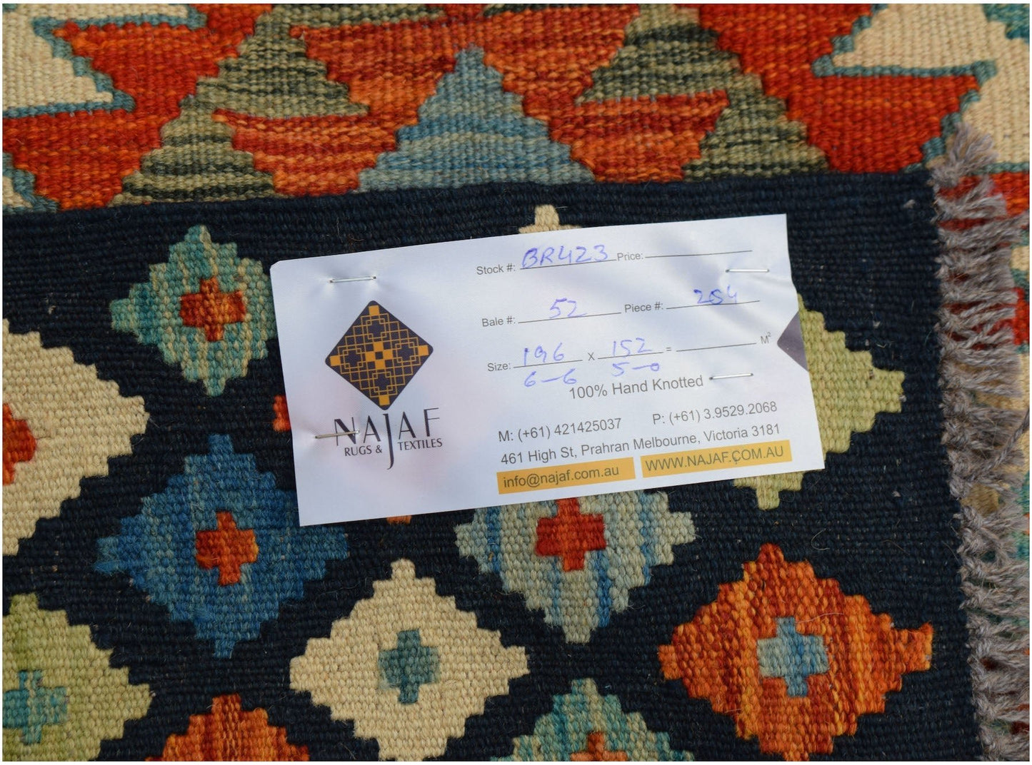 An Afghan Maimana Kilim rug featuring a geometric diamond pattern in orange, blue, and cream.
