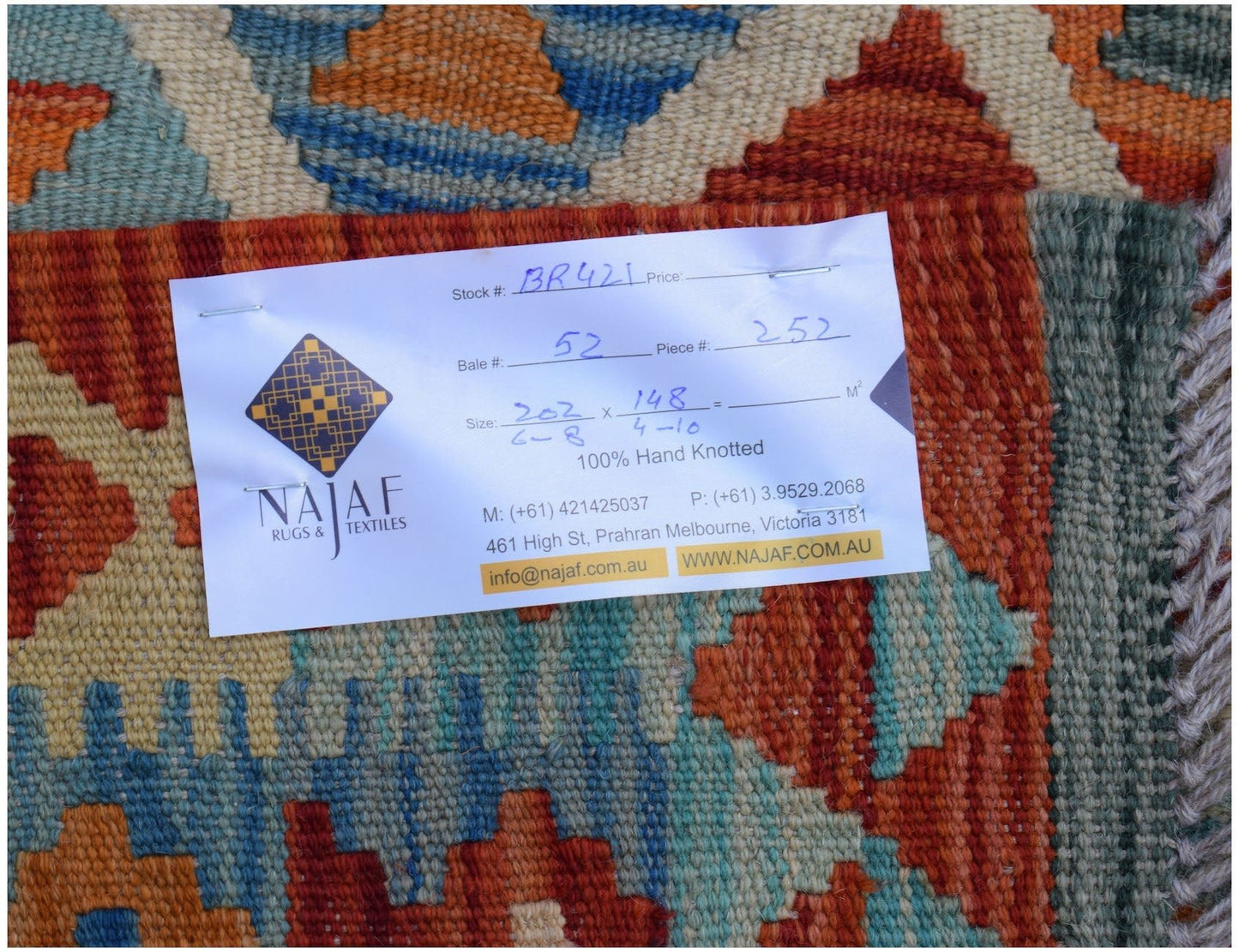 A handwoven Afghan Maimana kilim rug featuring a geometric pattern in orange, blue, and tan.