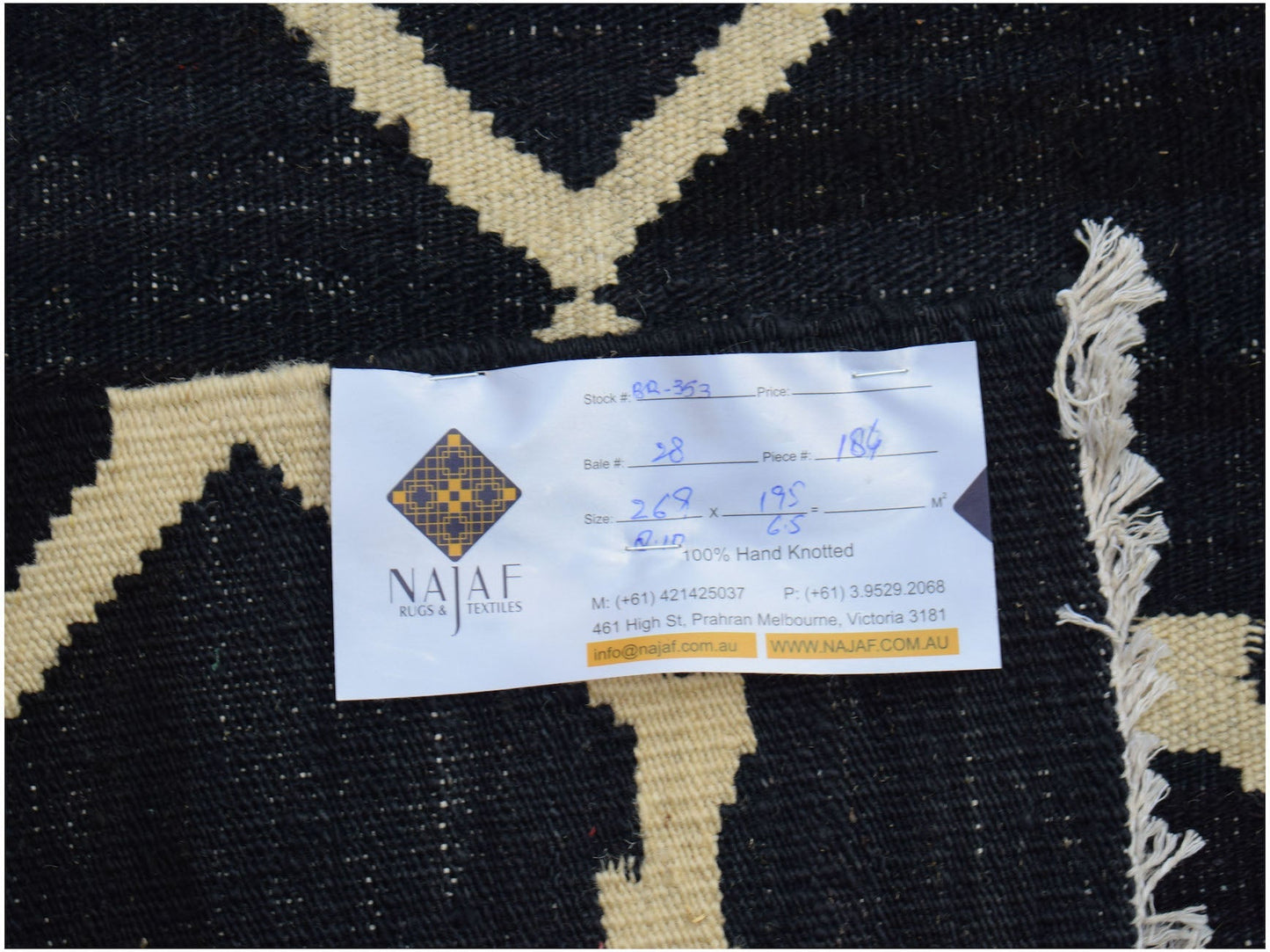 An Afghan Maimana kilim rug featuring a geometric pattern in black and cream wool.