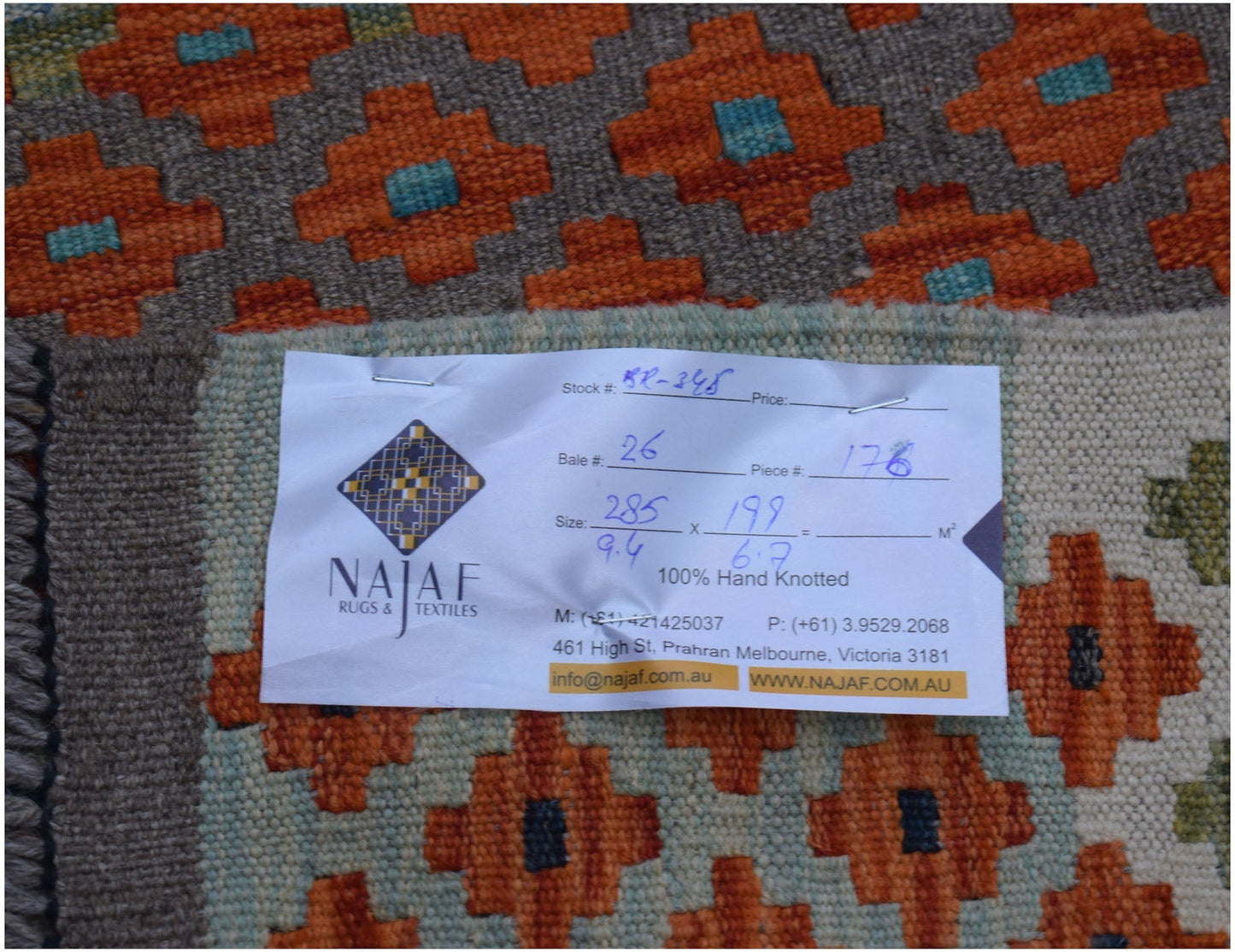 An Afghan Maimana Kilim rug featuring a geometric pattern in orange, brown, and teal tones.