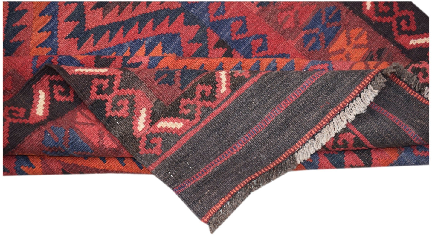 A handwoven Afghan Maimana kilim runner featuring geometric patterns in red, blue, and black wool.