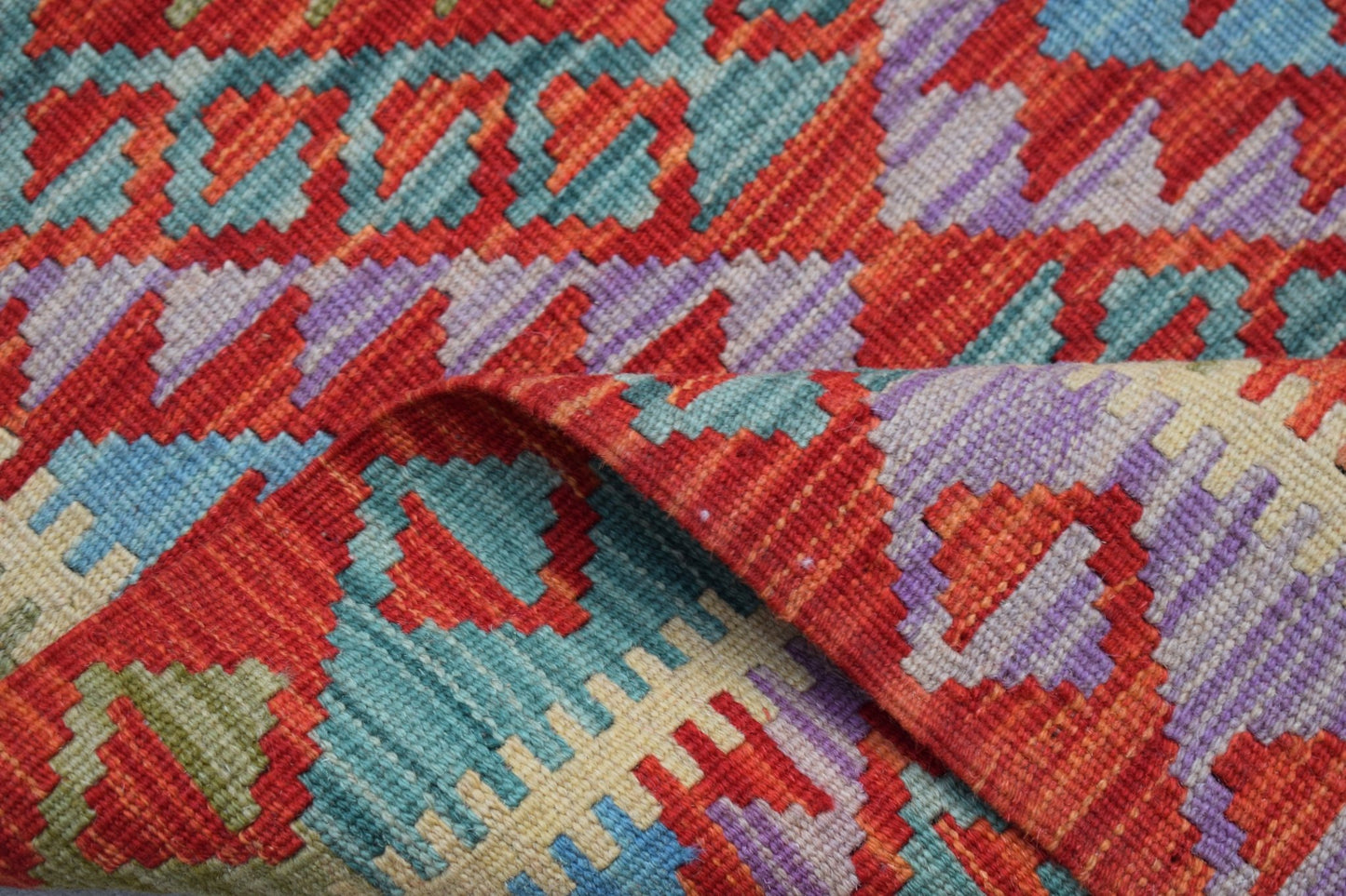 A handmade Afghan Maimana wool kilim runner featuring a vibrant geometric pattern.