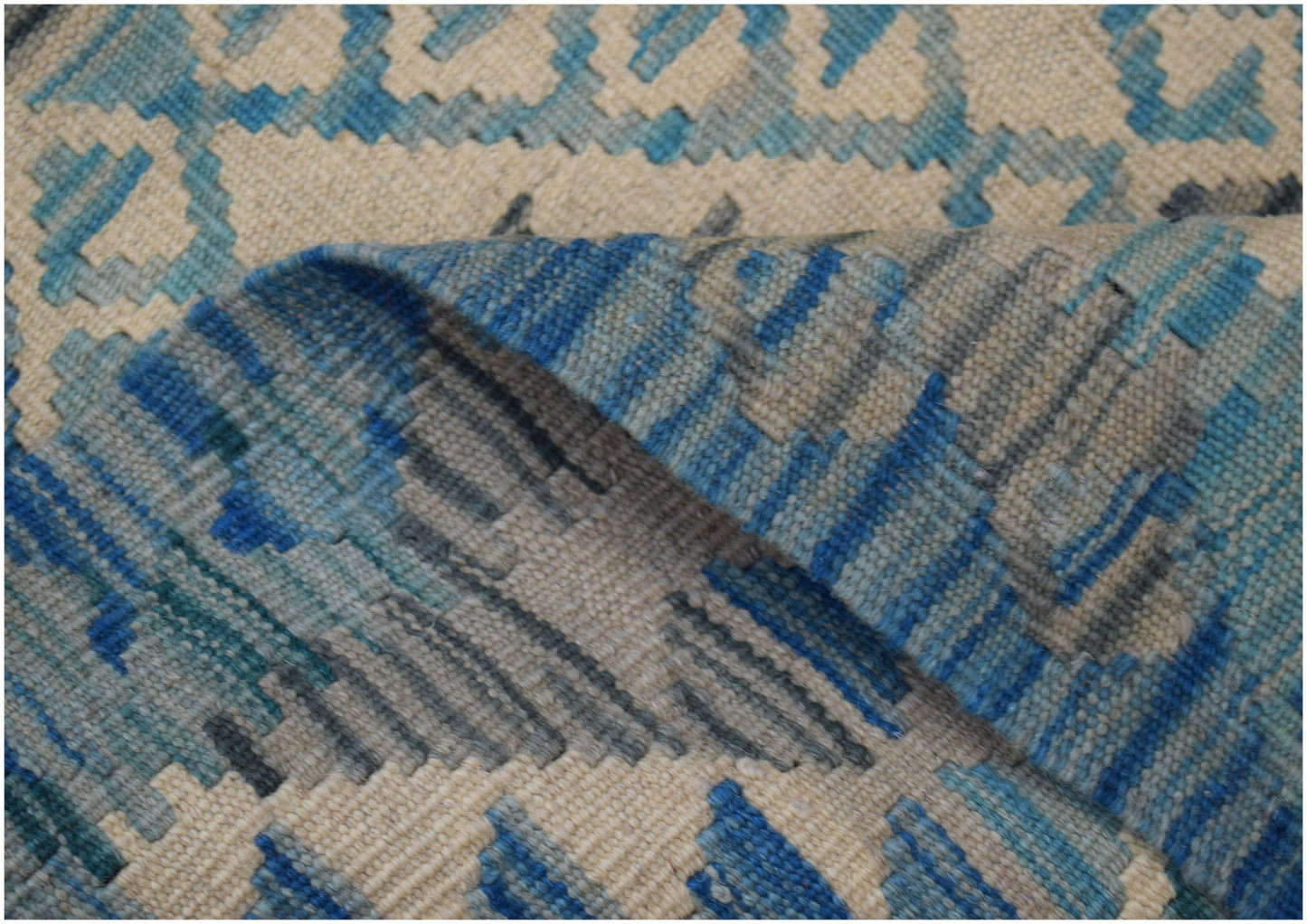 A handwoven Afghan Maimana wool kilim runner featuring a geometric pattern in blue and cream tones.