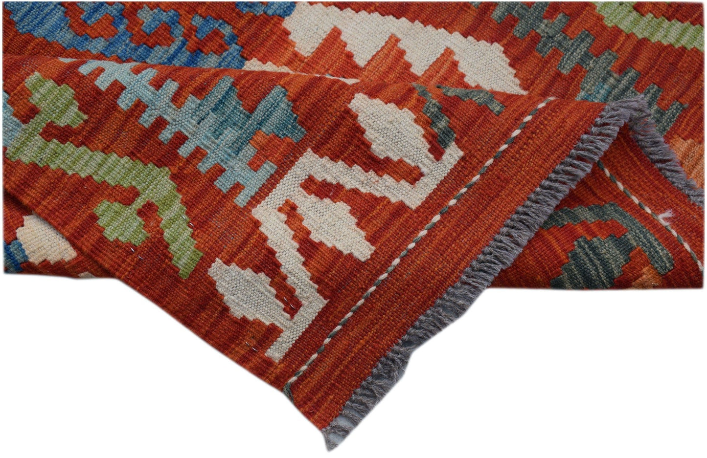A handwoven Afghan Maimana kilim runner featuring geometric patterns in red, blue, and green wool.