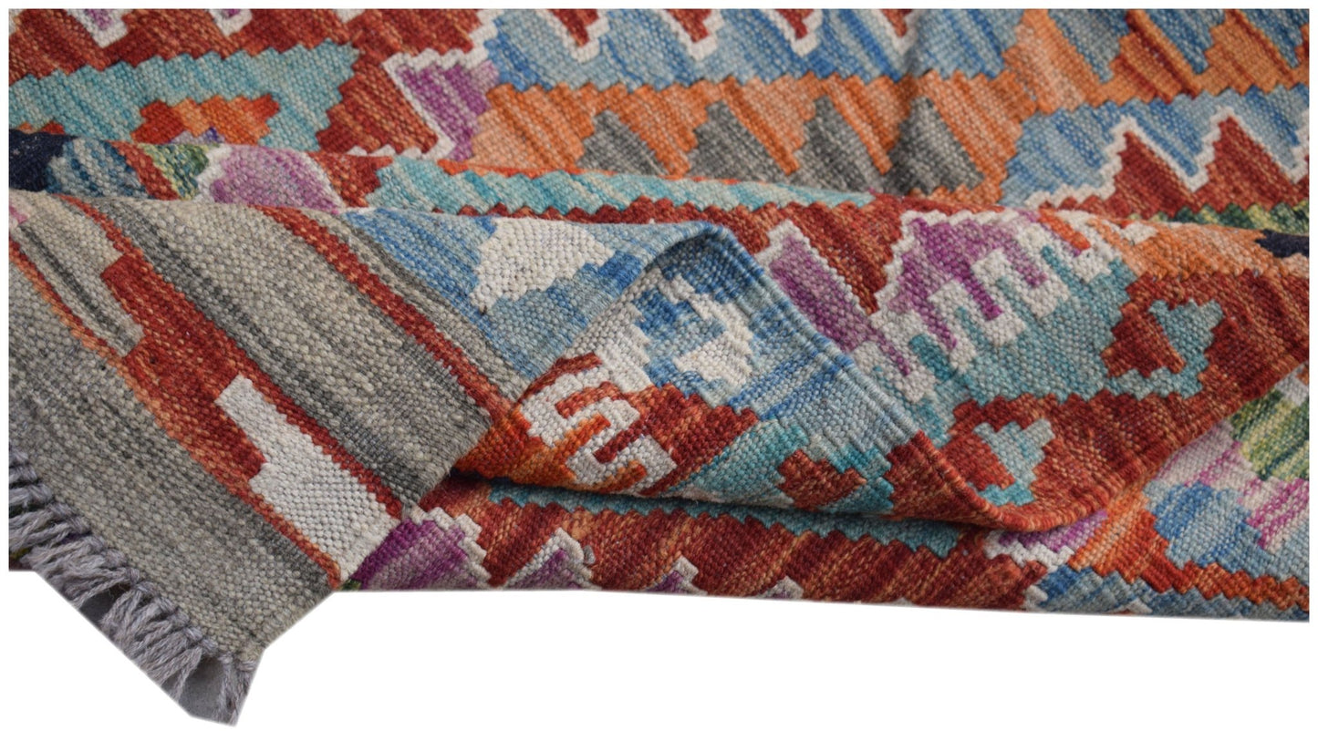 A handwoven Afghan Maimana Kilim runner featuring a vibrant geometric pattern in wool.