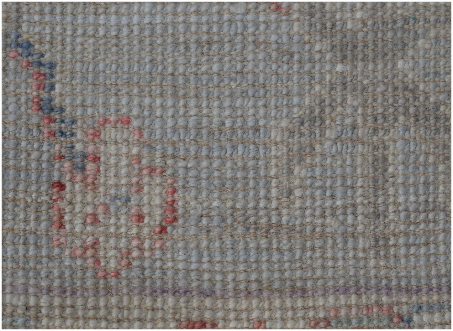 A close-up view of a handmade wool runner rug featuring a traditional pattern in soft muted tones.