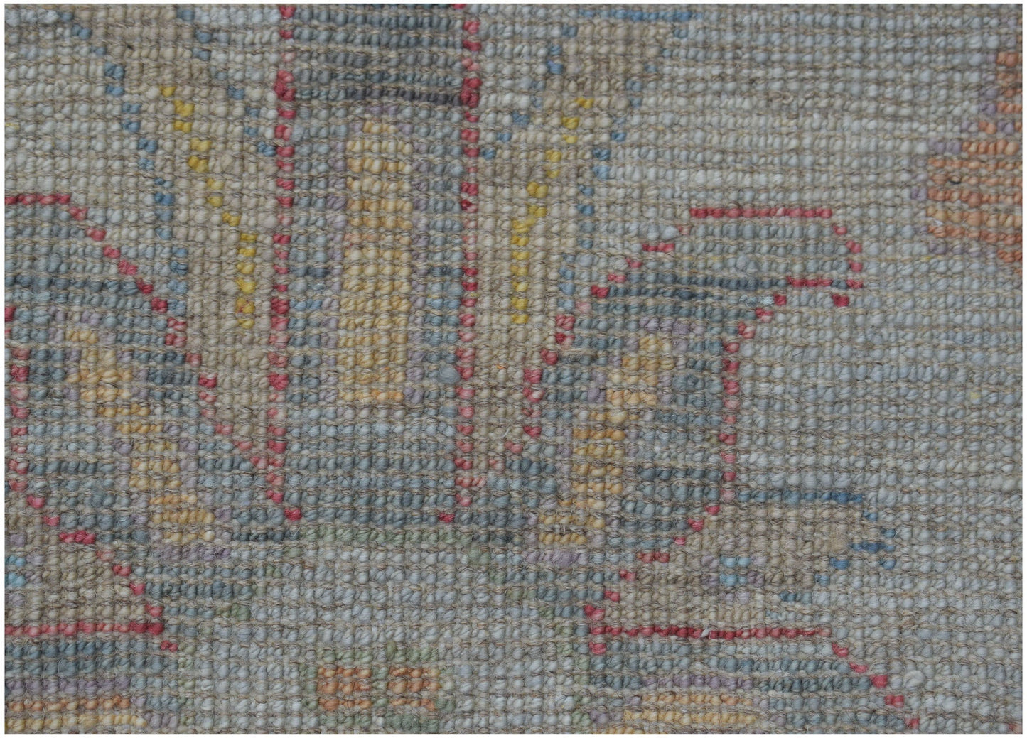 A close-up view of a handmade Afghan Oushak rug featuring a traditional pattern in muted tones.