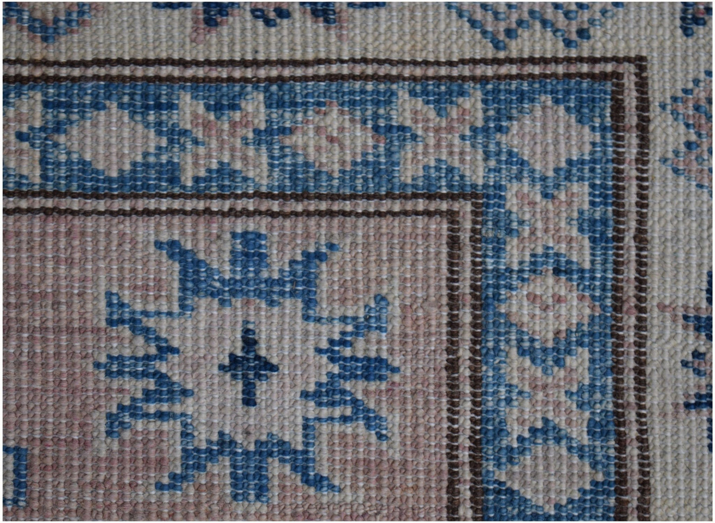 A close-up of an Afghan Super Kazakh runner featuring a blue and pink geometric floral pattern.