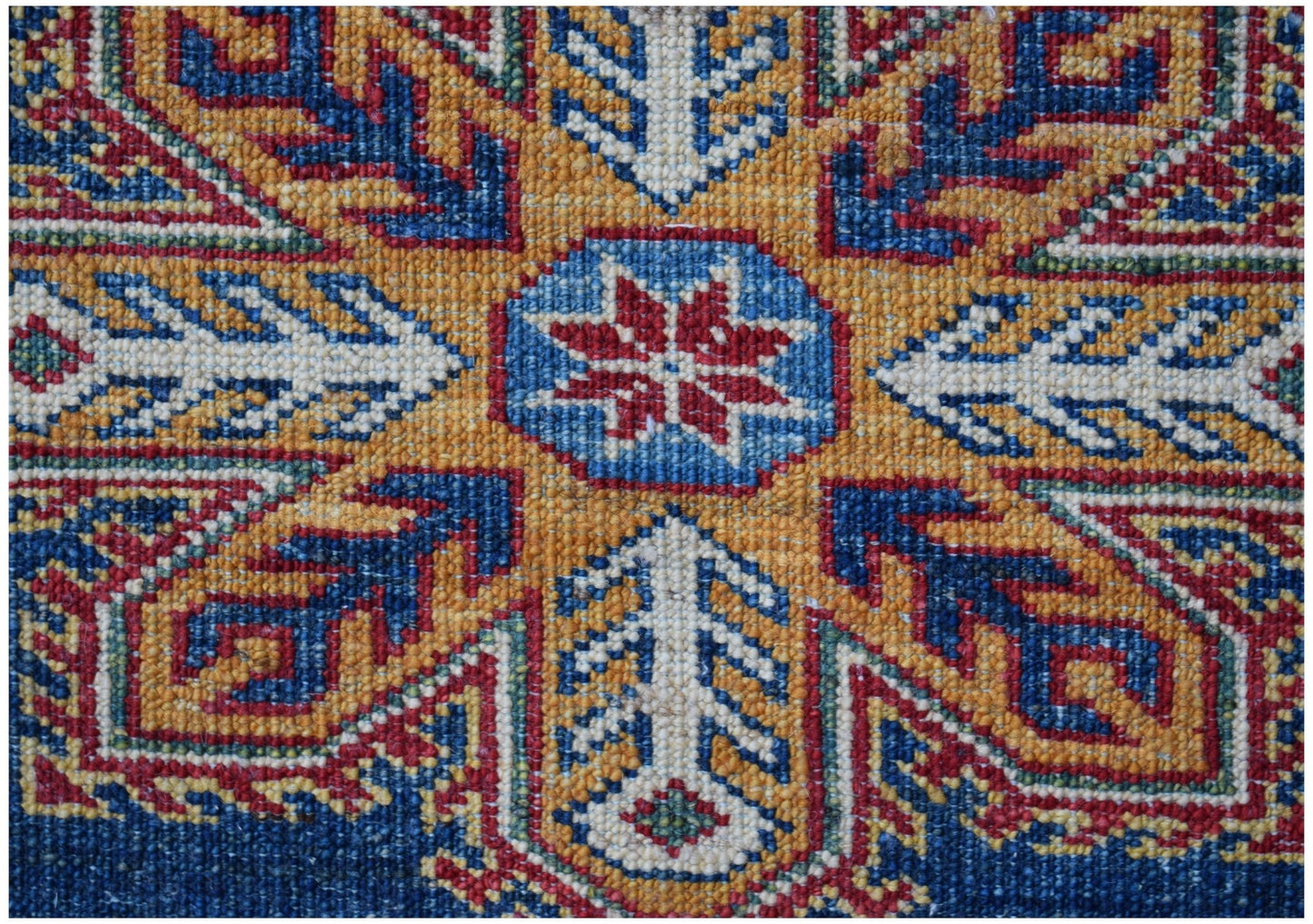 A close-up of an Afghan Super Kazakh rug featuring a central red star motif on a blue background.