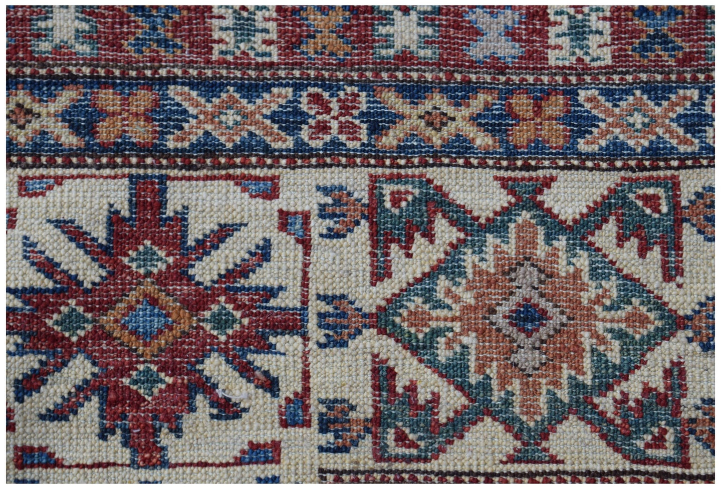 A handmade Afghan Super Kazakh rug featuring traditional geometric motifs in red, blue, and tan.