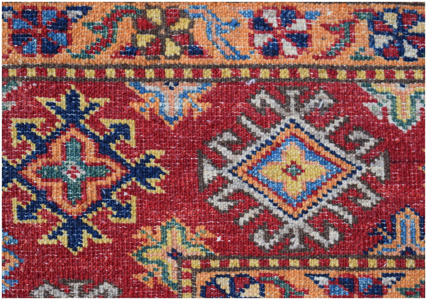A close-up of an Afghan Super Kazakh rug featuring traditional geometric motifs in red and blue.