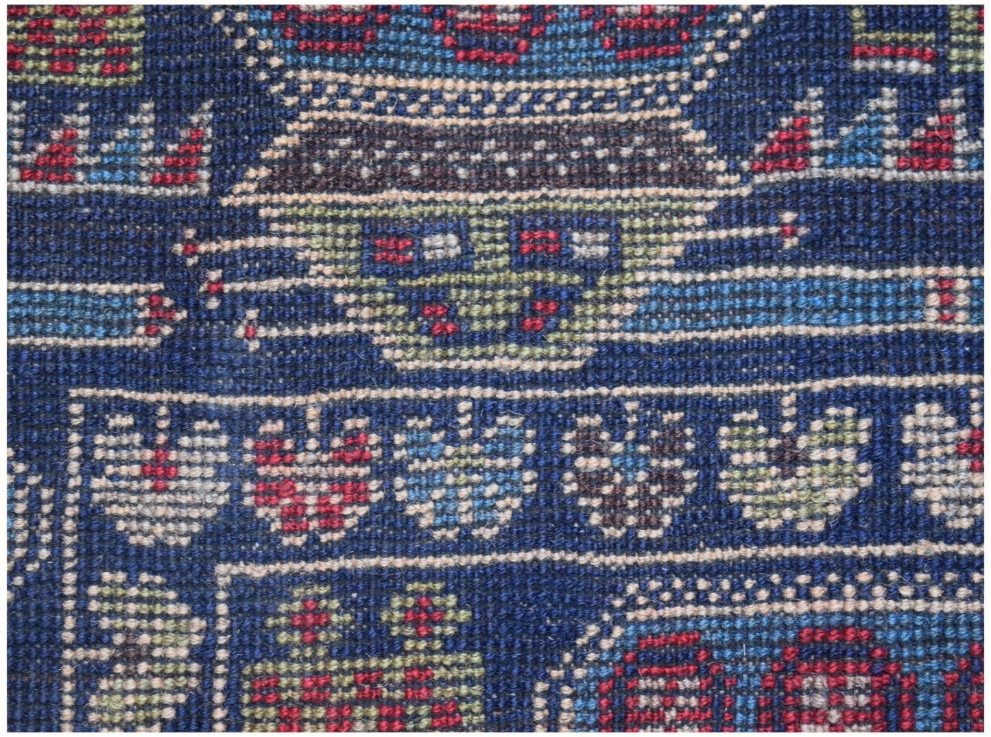 A close-up of a handmade Afghan wool rug featuring intricate geometric and floral patterns.