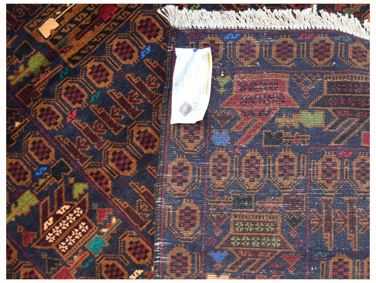 A handmade Afghan wool rug featuring traditional geometric patterns and a dark blue background.