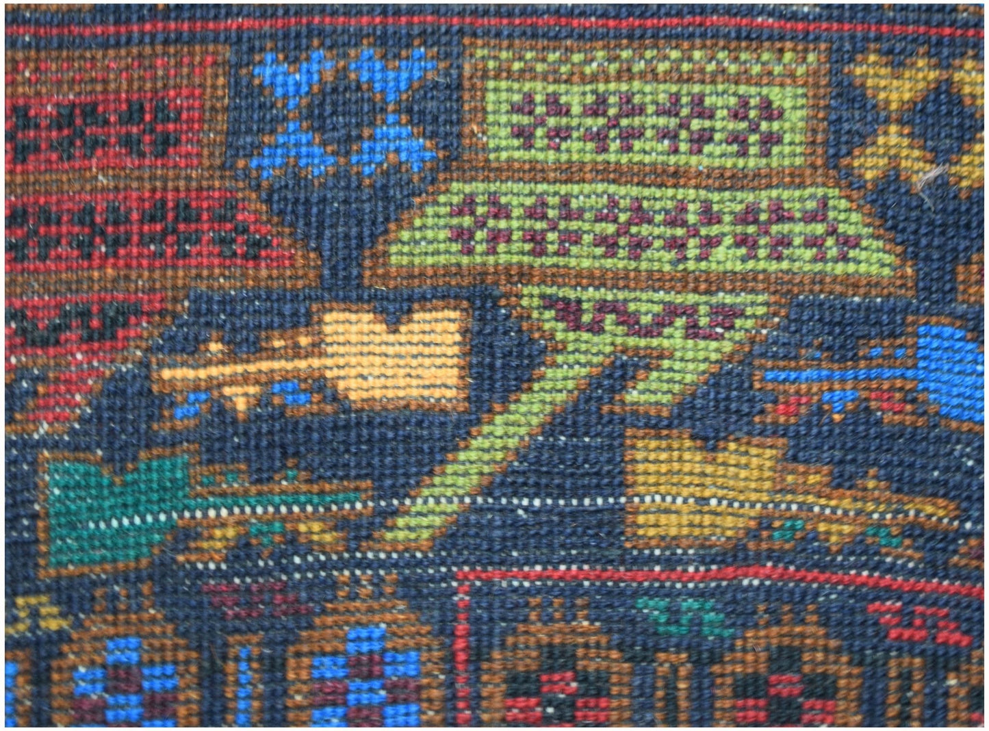 A close-up of a handmade Afghan wool rug featuring intricate geometric and symbolic patterns.