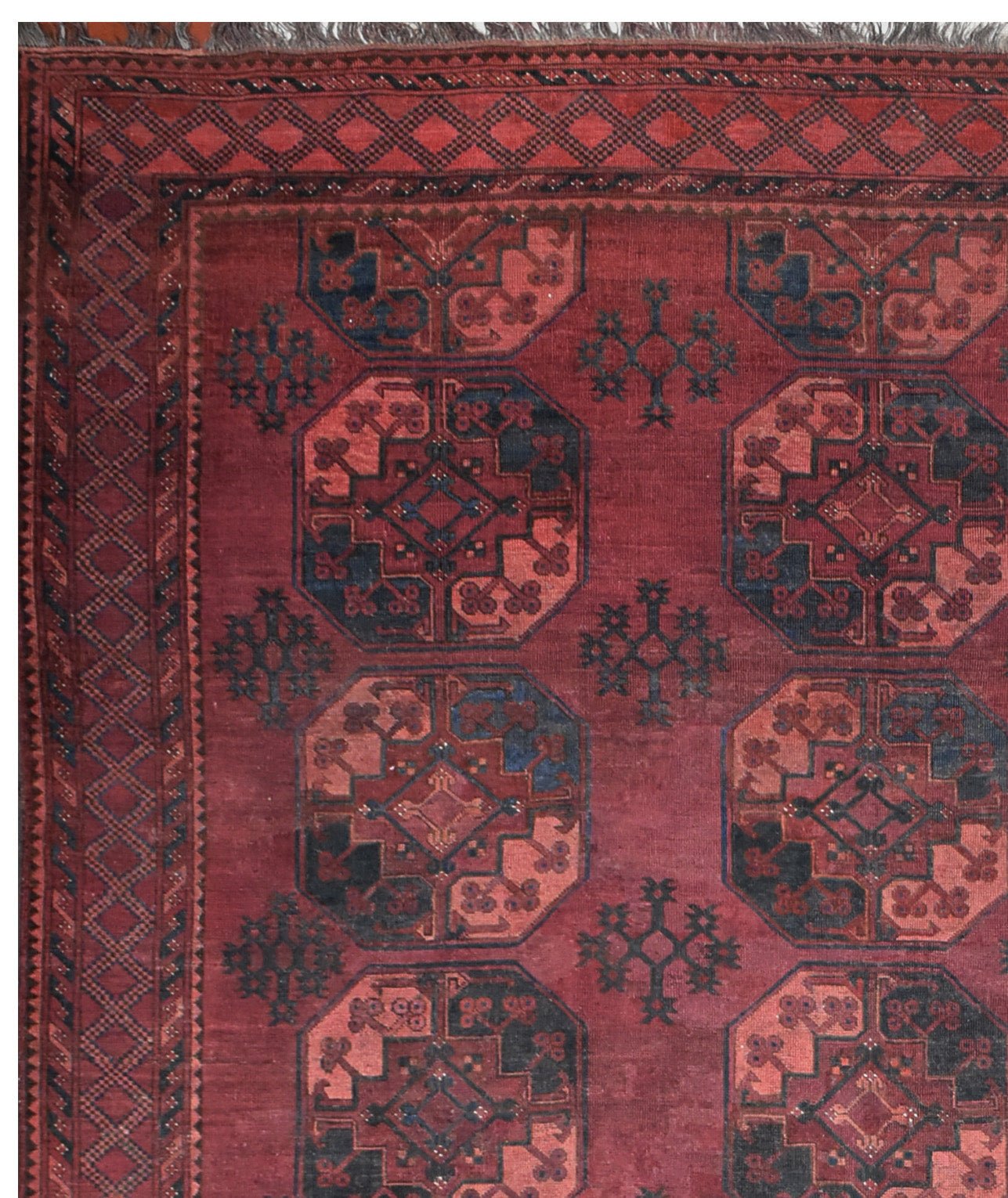 An antique Afghan Turkmen rug featuring a deep red field with repeating geometric octagonal motifs.