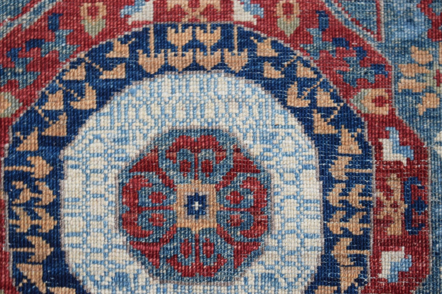 A close-up of a handwoven Afghan Chobi runner featuring a detailed blue and red Mamluk medallion.