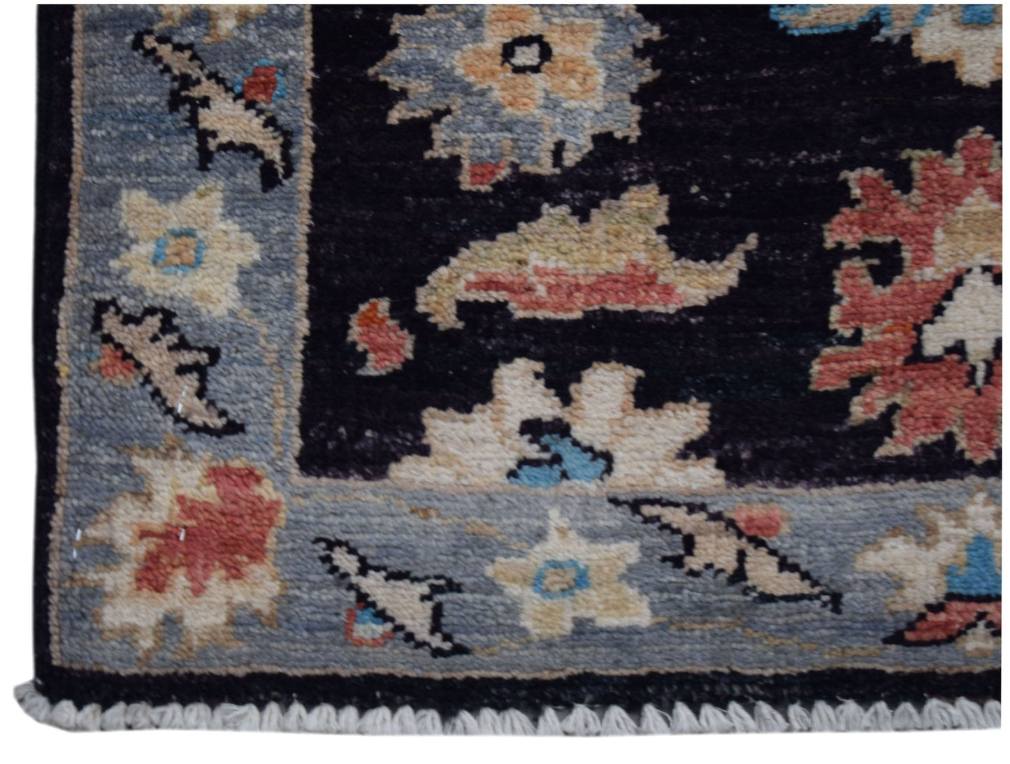 A handmade Afghan Chobi rug featuring a floral pattern in muted tones on a dark background.
