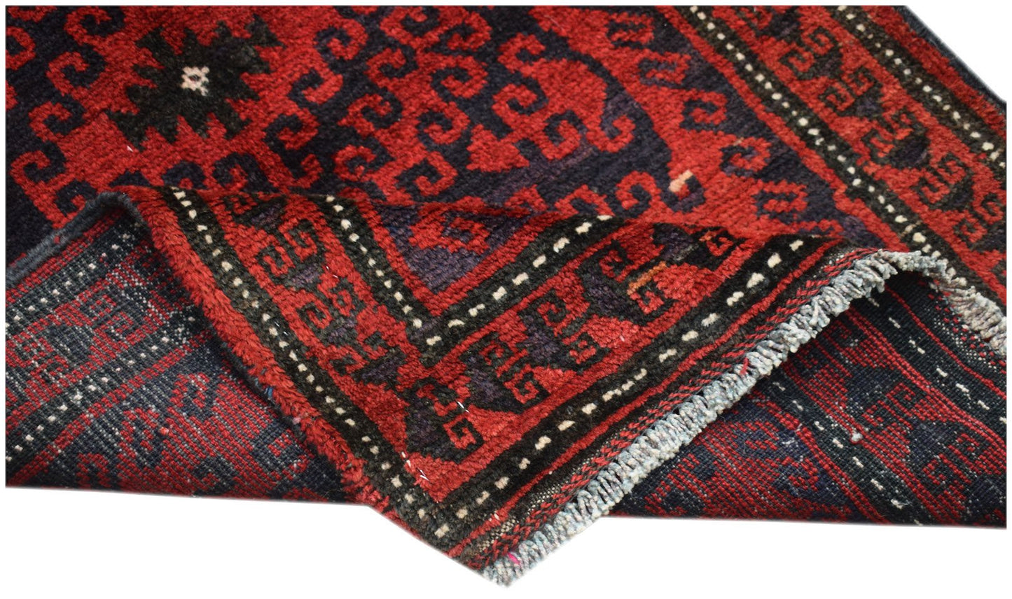 A vintage handmade Afghan Baluch wool rug featuring a geometric pattern in red and dark blue.