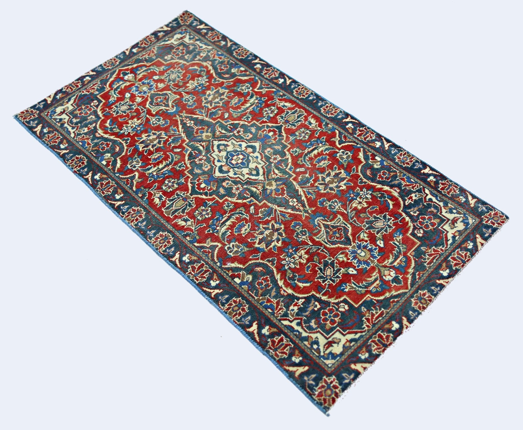 A rectangular vintage Persian rug featuring a traditional floral pattern in red, blue, and cream.