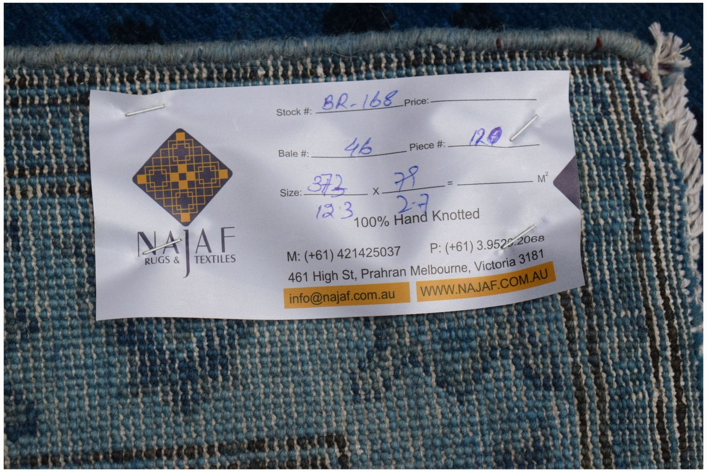 A close-up view of the back of an overdyed Afghan Chobi runner with a product label attached.