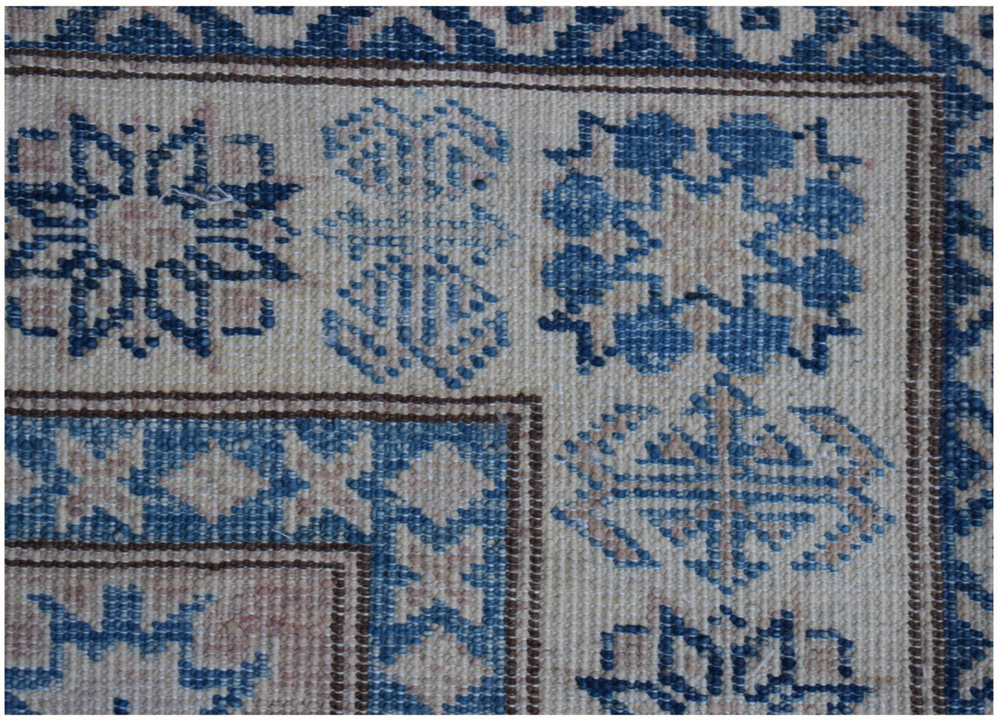 A close-up of an Afghan Super Kazakh runner rug featuring geometric blue and beige patterns.