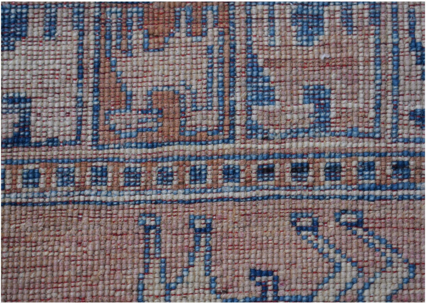 A close-up of a handmade Afghan Chobi rug featuring geometric patterns in blue, beige, and grey.