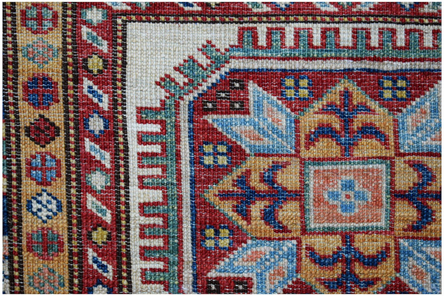 A close-up of an Afghan Super Kazakh runner featuring traditional geometric motifs in vibrant colors.