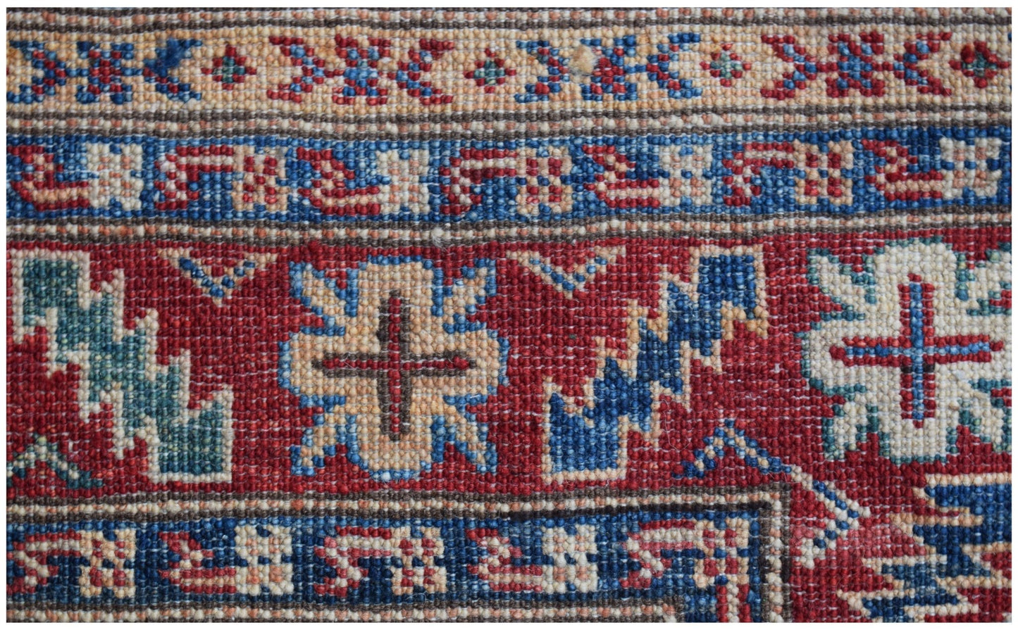 A close-up of an Afghan Super Kazakh runner featuring traditional geometric motifs in red and blue.