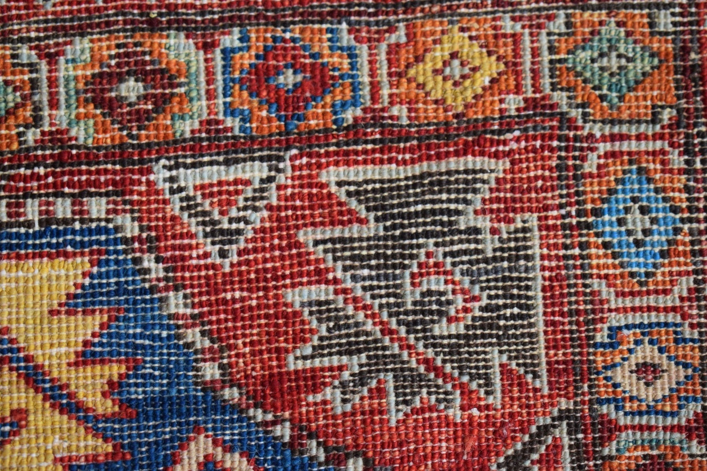 A close-up of a handmade Afghan Chobi rug featuring intricate geometric patterns in vibrant colors.