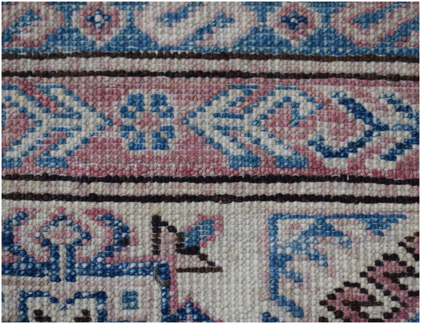 A close-up of a handmade Afghan Super Kazakh rug featuring traditional blue and pink geometric motifs.