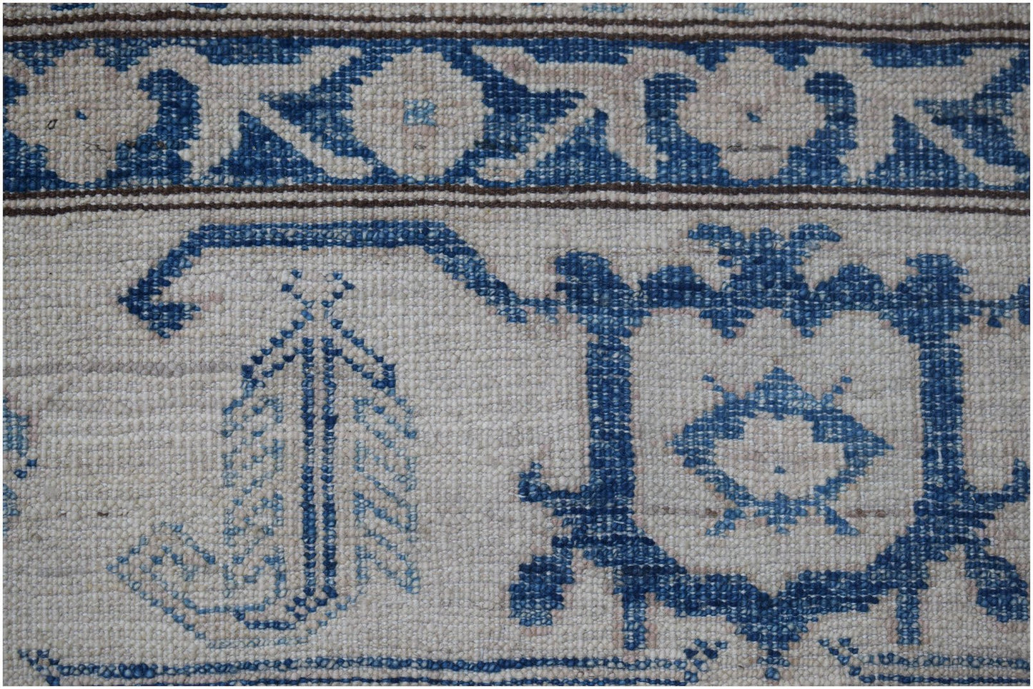 A close-up of an Afghan Super Kazakh rug featuring traditional blue geometric motifs on cream wool.