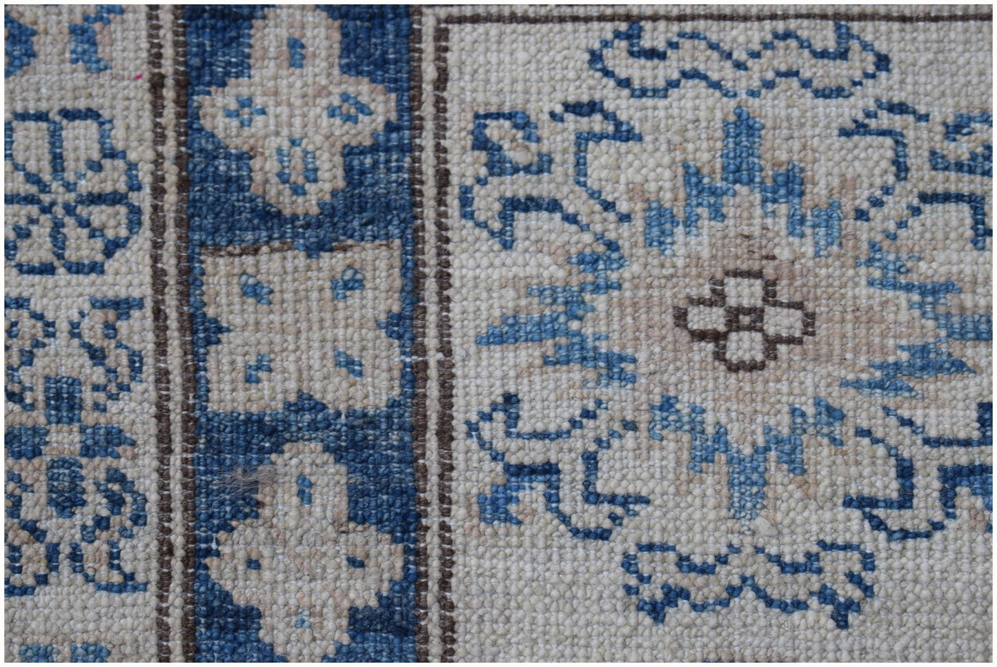 A close-up of an Afghan Super Kazakh rug featuring blue and cream geometric floral patterns.