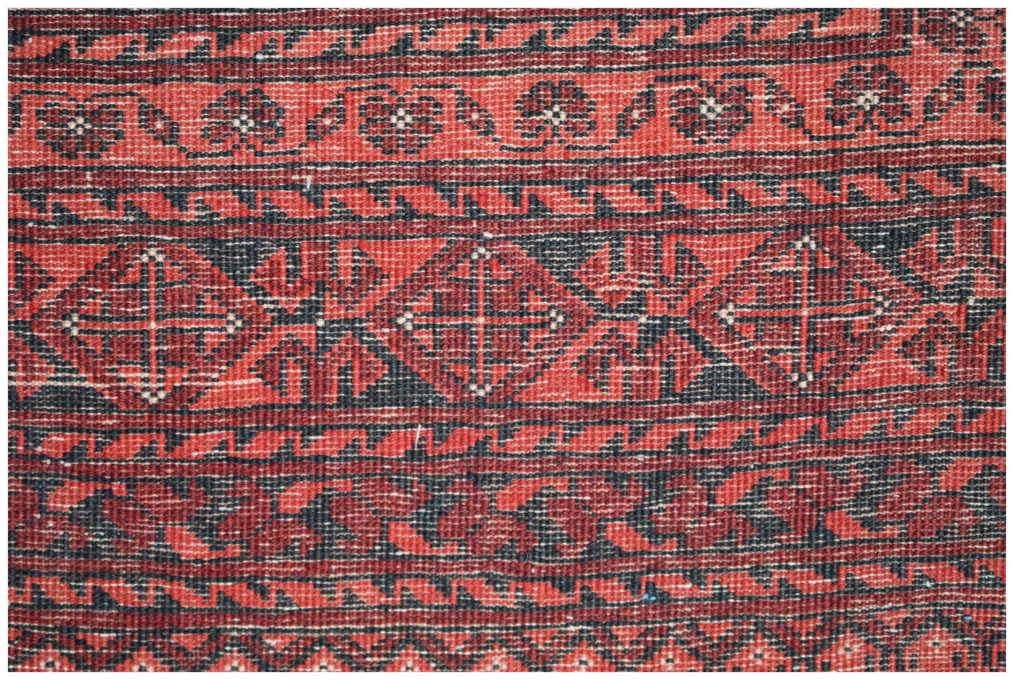 A vintage Afghan Turkmen rug featuring a geometric elephant foot motif in red and black wool.