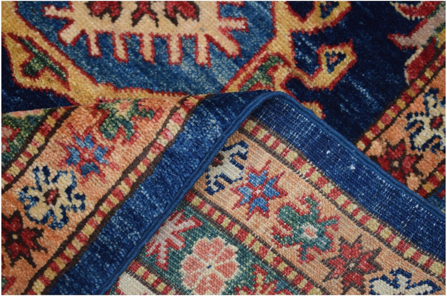 A close-up view of a handmade Afghan Super Kazakh rug featuring intricate geometric patterns.