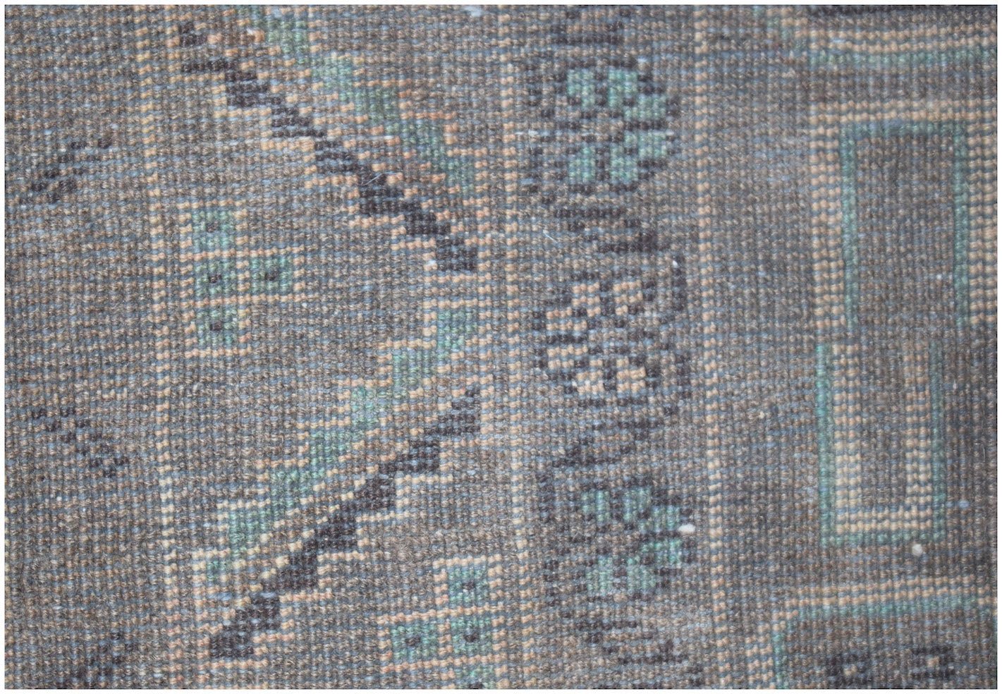 A close-up of a vintage Afghan Baluch runner featuring geometric patterns in blue and brown wool.