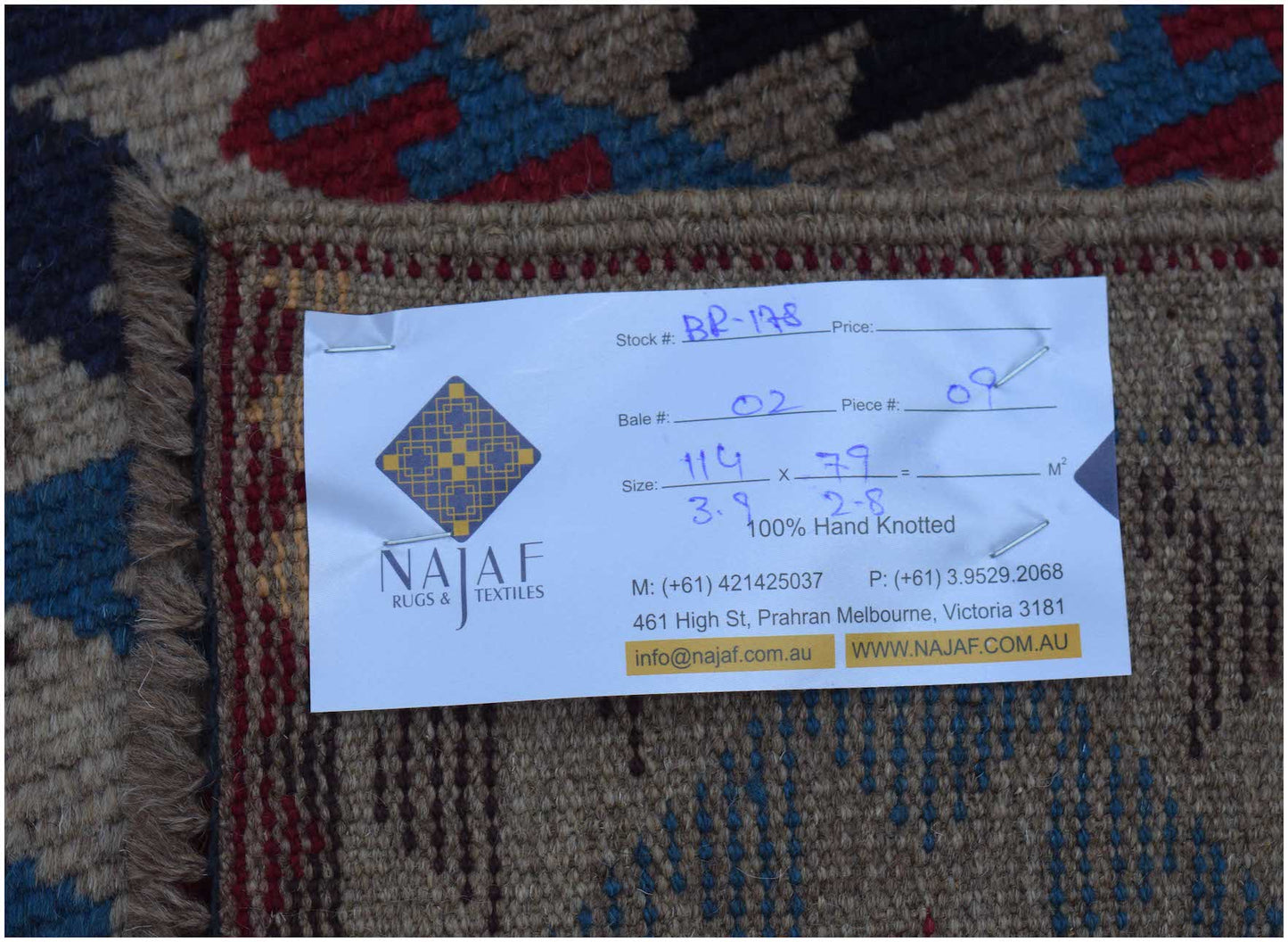 A handmade Afghan Pashm rug featuring a traditional tribal pattern in shades of red, blue, and brown.