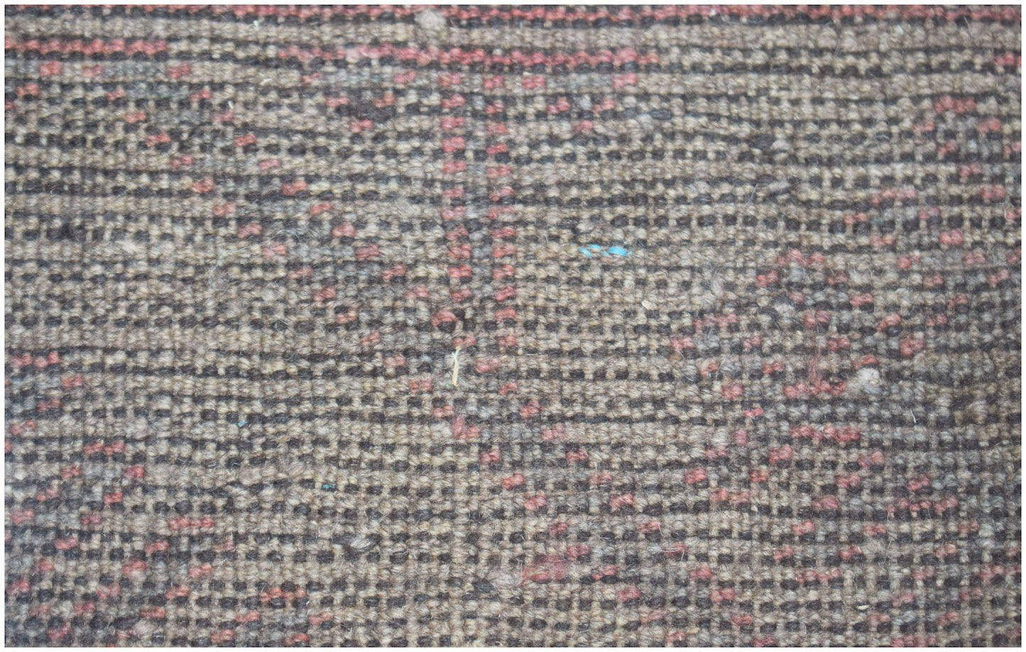A close-up of a handmade Afghan Baluch rug featuring a textured, geometric pattern in wool.