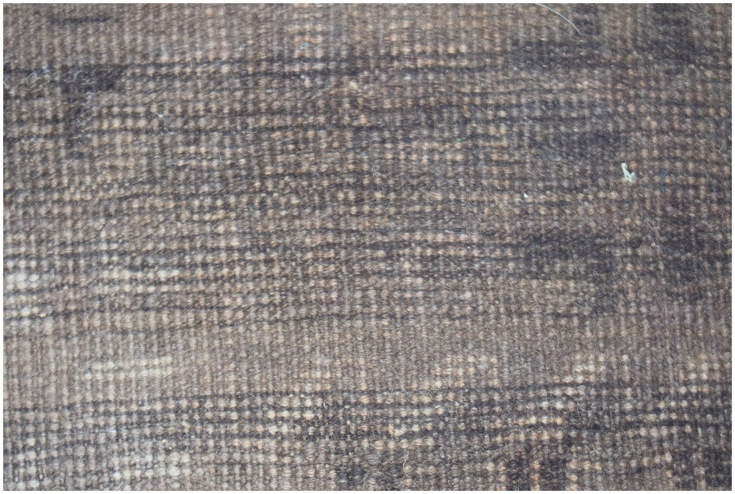 A close-up view of a handmade Afghan Baluch rug featuring a dark, textured wool pattern.