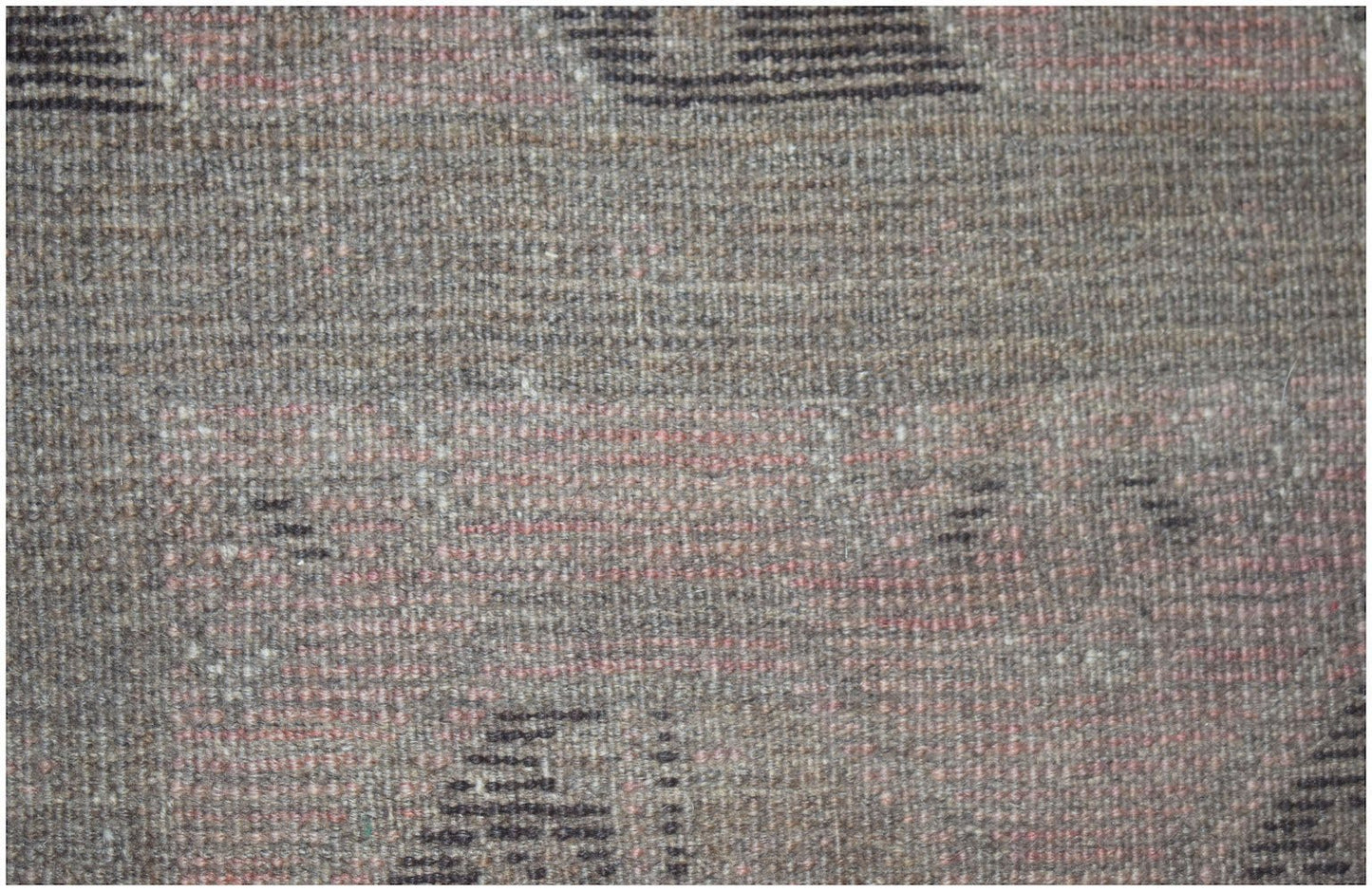 A close-up of a handmade Afghan Baluch rug featuring a textured wool weave in earthy tones.